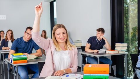 Eine Studierende meldet sich im Unterricht, vor ihr liegen einige Gesetzestexte.
