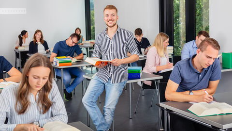 Auszubildender im Lehrsaal mit einem Buch in der Hand