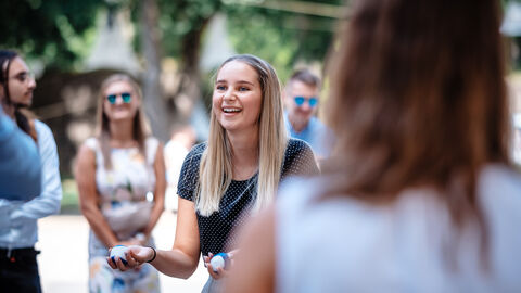 Eine Anwärterin hält zwei Jonglierbälle und lacht