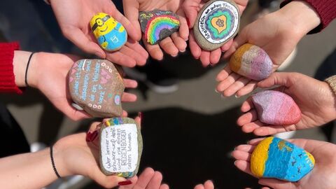 Hände halten bunt bemalte Steine in der Hand