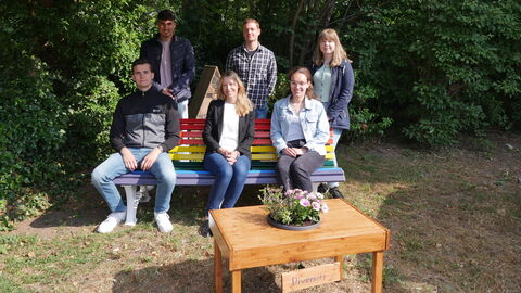Anwärter*innen aus Dieburg sitzen auf einer bunt bemalten Bank. 