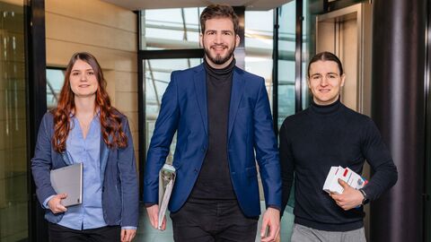 Drei Studierende laufen auf einen zu