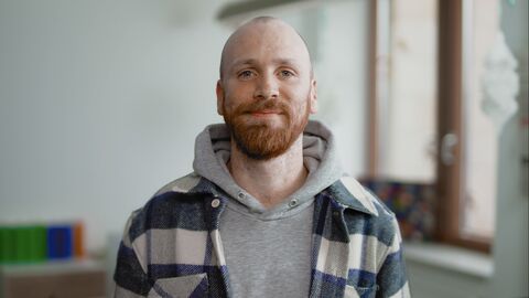 Patrick ist ein junger Mann mit kurzen Haaren. Er trägt einen Pullover und steht im Finanzamt.